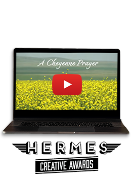 An open laptop with a video still of a field covered in yellow flowers and the text "A Cheyenne Prayer - Hermes Creative Awards