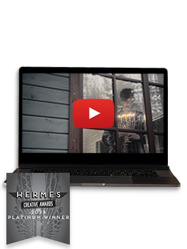 An open black laptop with a still from a video with a man holding a menorah at the window - Hermes Creative Awards 2024 Platinum Winner